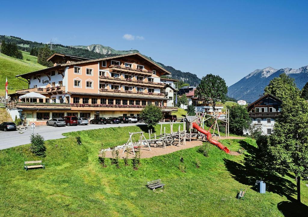 ein großes Gebäude mit einem Spielplatz im Gras in der Unterkunft Hotel Rustika in Lermoos