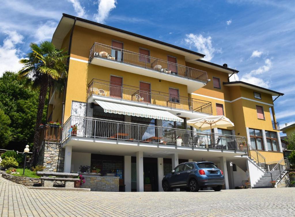 żółty budynek z samochodem zaparkowanym przed nim w obiekcie Albergo Ristorante Innocenti w mieście Ardenno