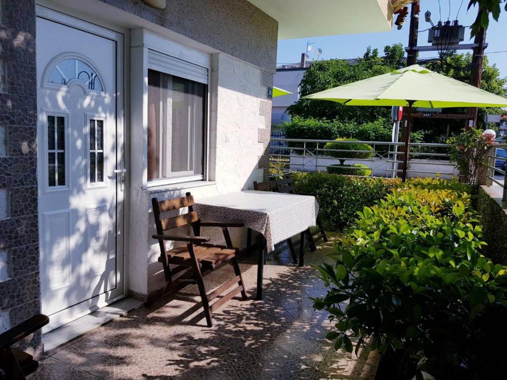 a patio with a table and a chair and an umbrella at Konstantinos-Elli Rooms in Nea Vrasna