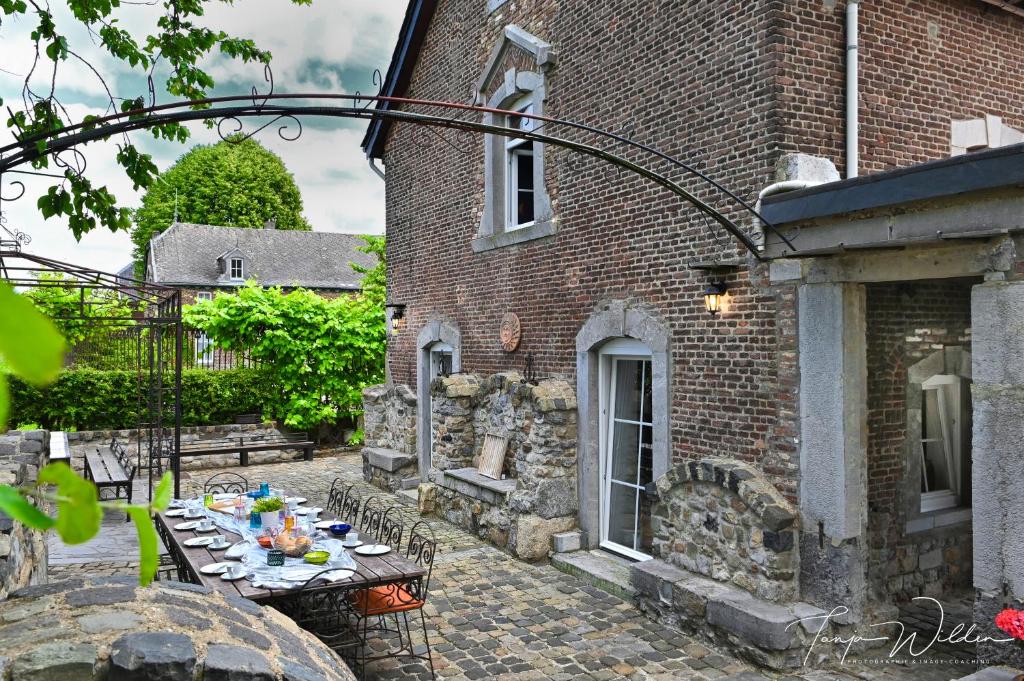 um pátio com uma mesa em frente a um edifício de tijolos em Landhaus Lontzen em Lontzen