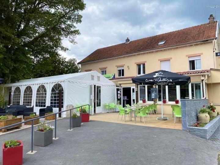 a white tent next to a building with tables and chairs at Hotel restaurant Robinson in Haybes