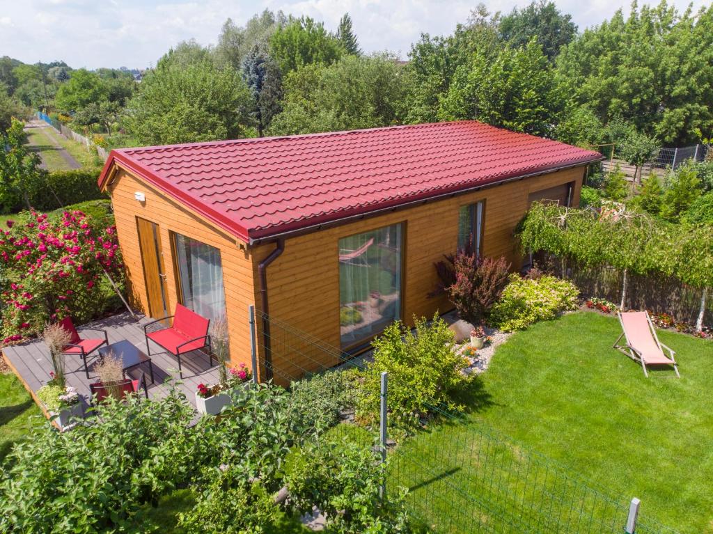 Różany Domek في غروجونتس: منزل صغير بسقف احمر في حديقة