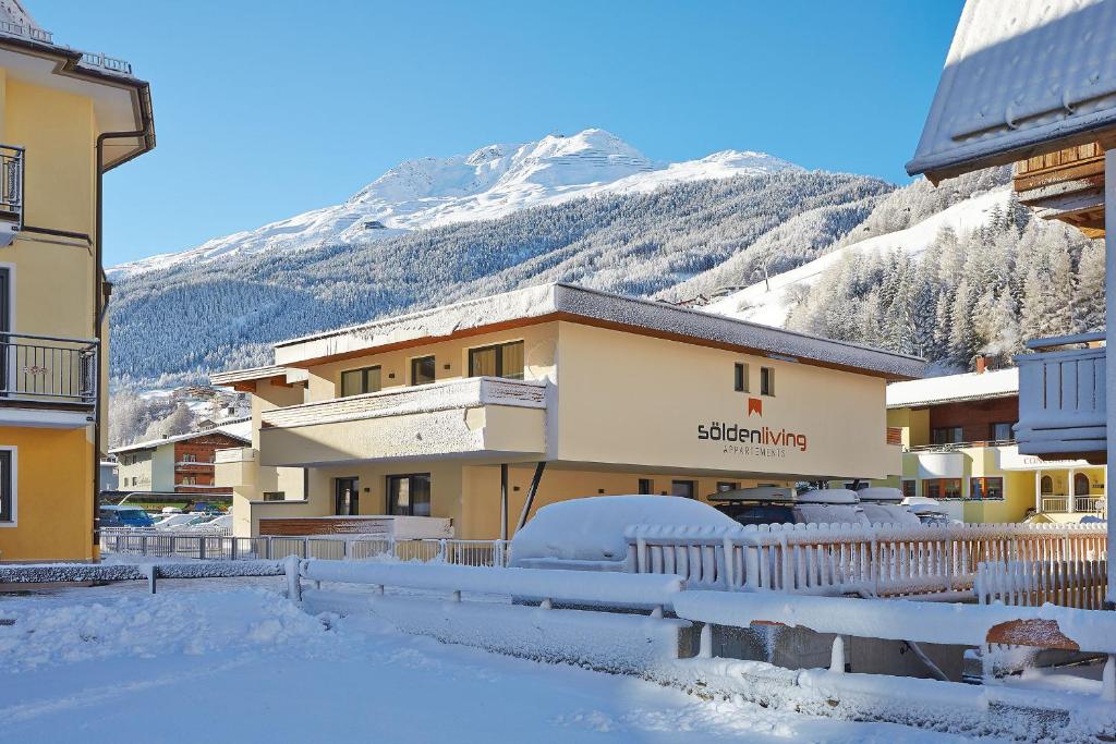 a snow covered building with a mountain in the background at SöldenLiving Appartements in Sölden