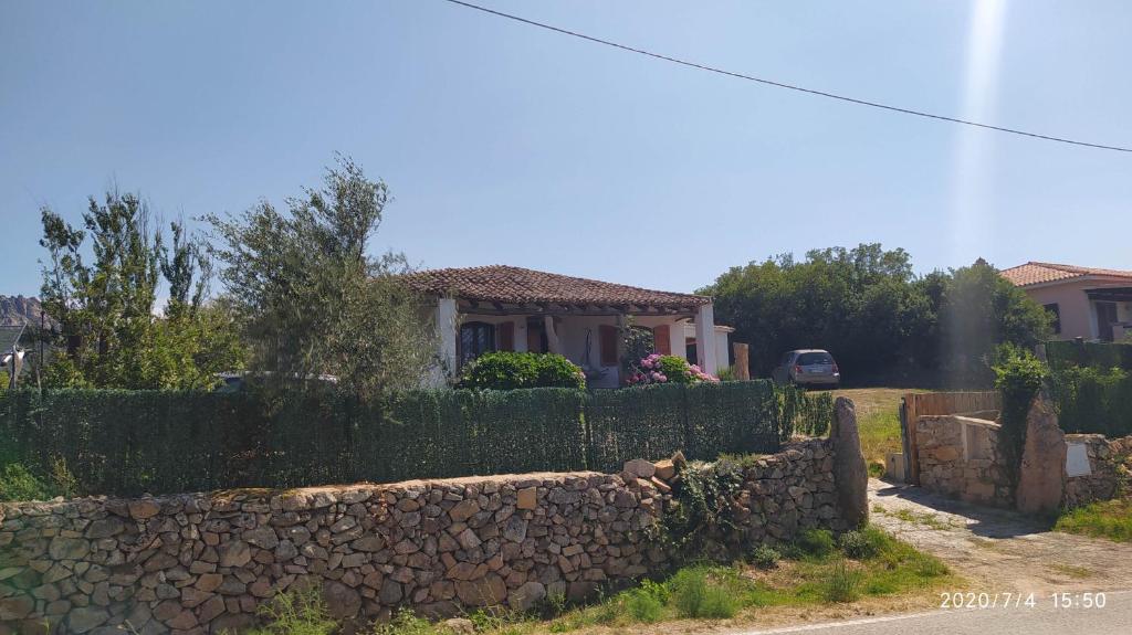 una casa con una valla de piedra frente a un patio en Portocervo House, en Arzachena