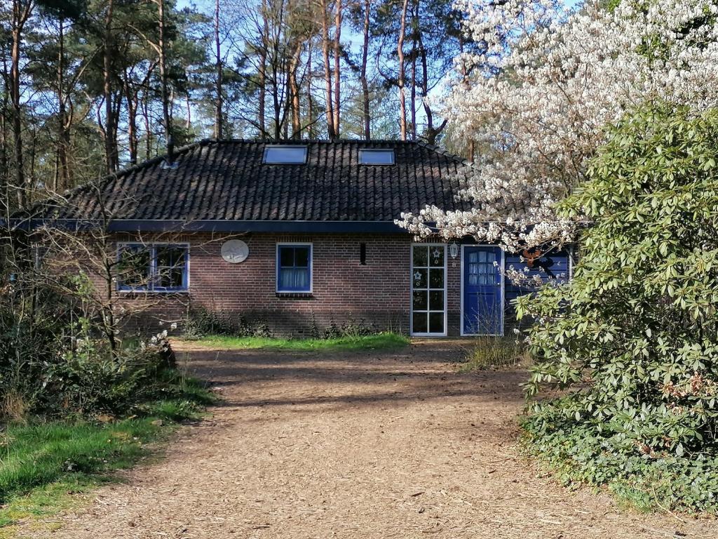 an old brick house with a blue door at Holiday home bos en heide in Otterlo