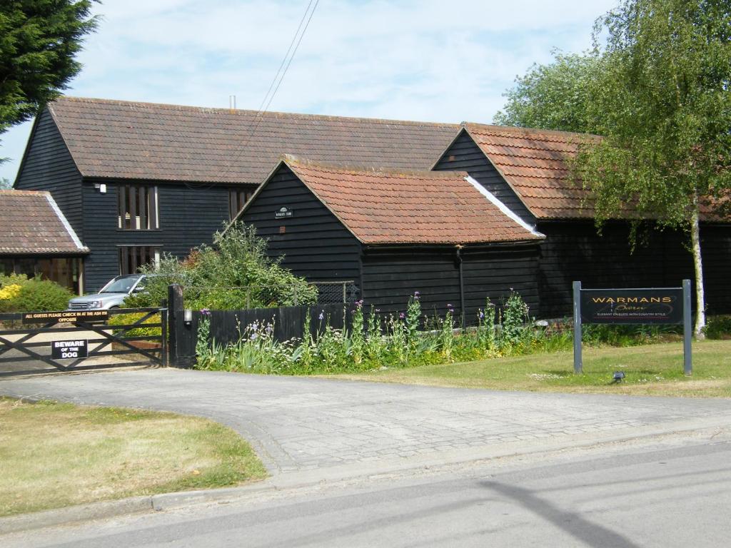 a black building with a sign in front of it at Warmans Barn in Stansted Mountfitchet