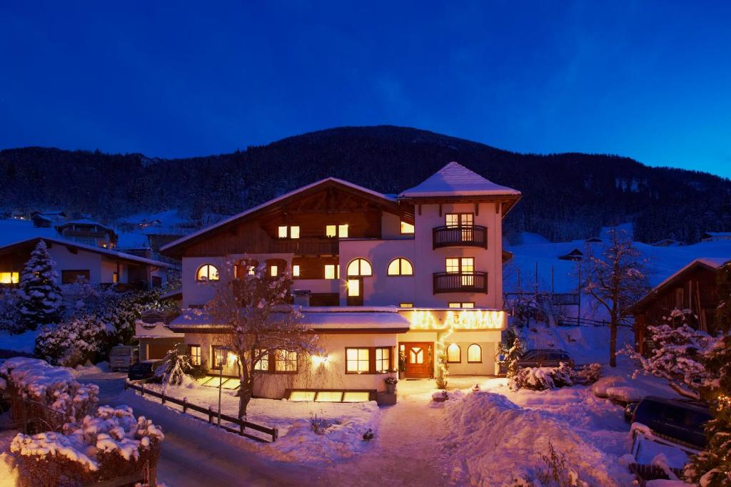 Ferienhotel Bergland im Pitztal: Gemütliche Außenansicht mit traditioneller alpiner Architektur im Schnee, Bäumen und Bergen im Hintergrund
