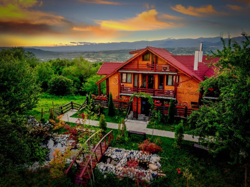 a wooden house with a garden in front of it at Pensiunea La Maria Lu' Sandoiu in Poenari