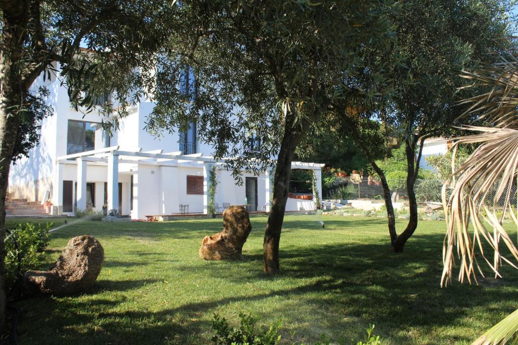 une maison blanche avec des arbres dans la cour dans l'établissement Villa La Conchiglia Rooms, à Cala Liberotto