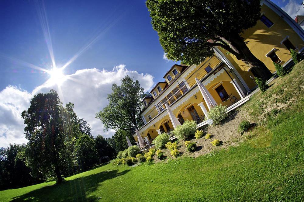 um grande edifício amarelo em uma colina gramada com o sol em Kastiel Lucivna em Lučivná