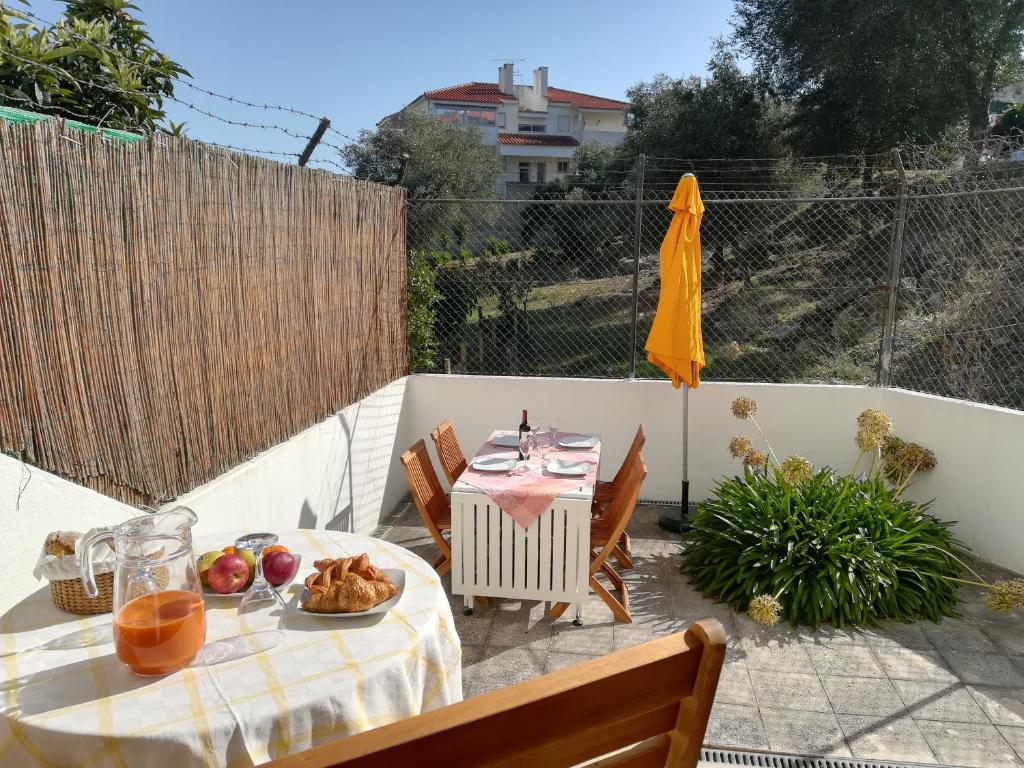 a patio with a table and chairs and an umbrella at Cosy apartment with terrace in Alcabideche