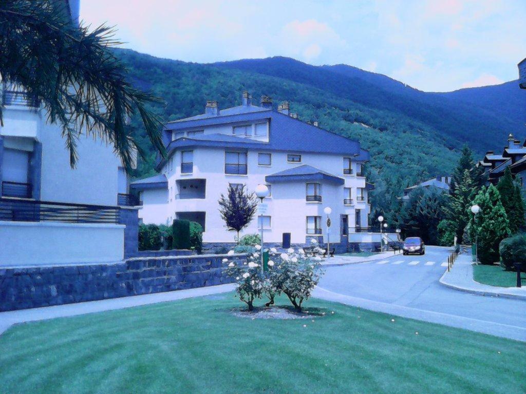 una gran casa blanca con un árbol en el patio en apartamento Valles Blancos 3-6, en Biescas