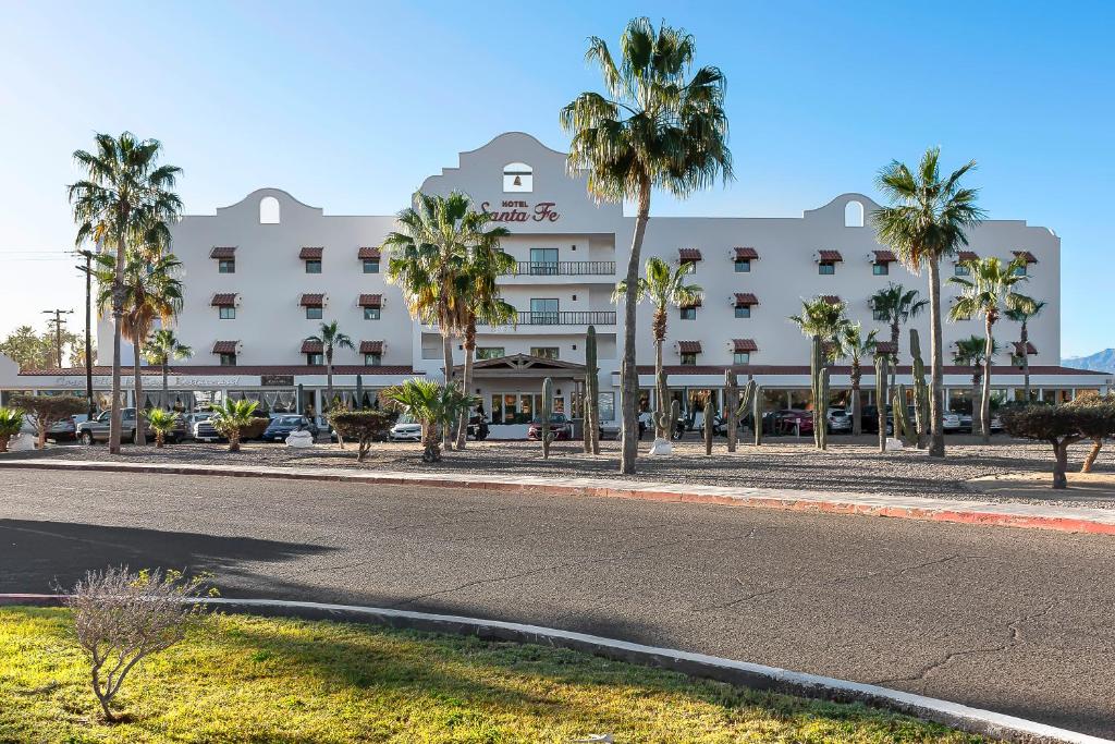 a building with palm trees in front of a street at Hotel Santa Fe Loreto by Villa Group in Loreto