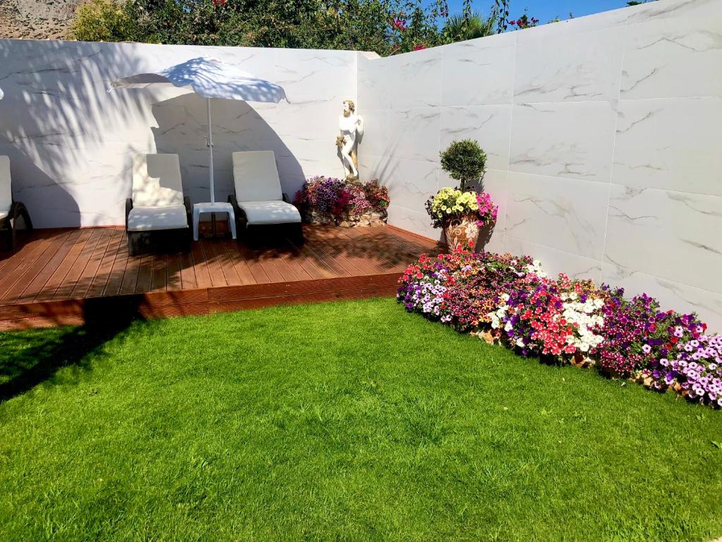 a garden with two chairs and flowers on a wooden deck at Paradice Hotel Luxury Suites-Near zorbas Beach-FREE Breakfast in Stavros
