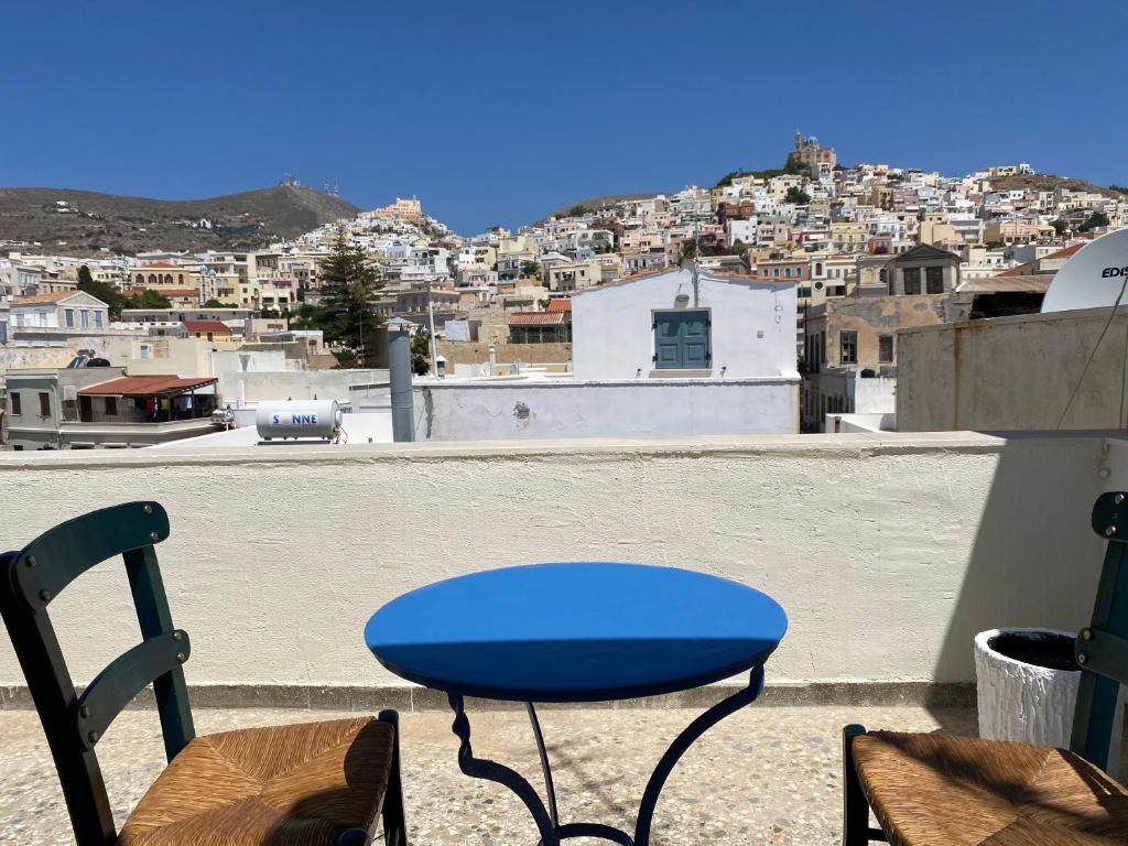 a blue table and chairs on a balcony with a city at Porto in Ermoupoli