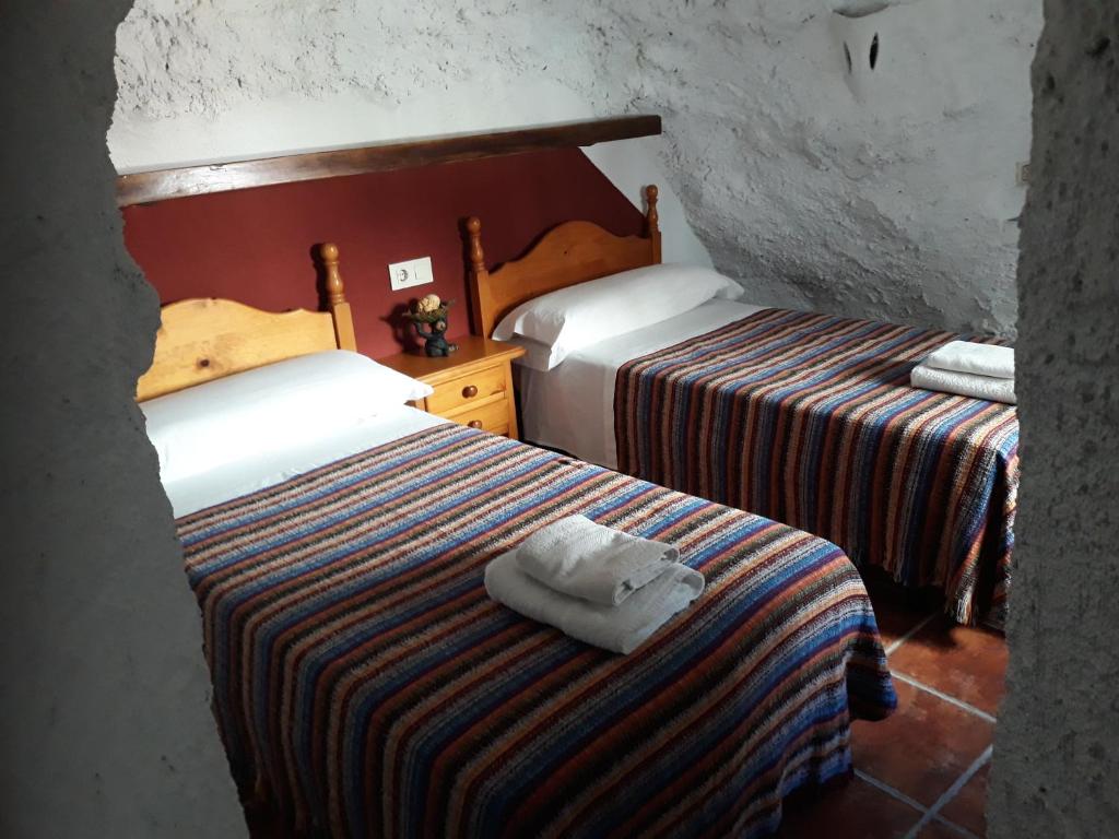 Pokój hotelowy z 2 łóżkami i ręcznikiem na łóżku w obiekcie Casa Rural Cueva El Sauce w mieście Pegalajar