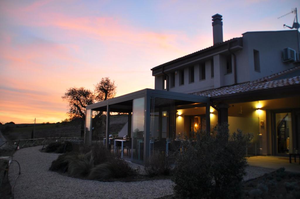 a white house with a sunset in the background at Agriturismo Le Piccole Macìe in Magliano in Toscana