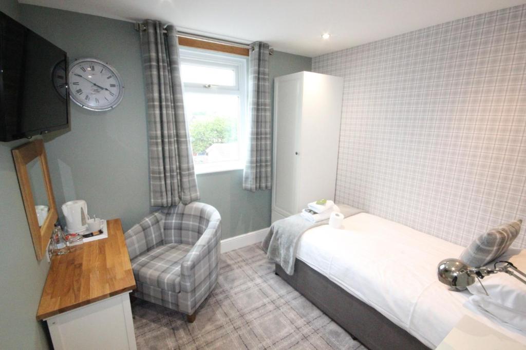 a bedroom with a bed and a chair and a clock at The Sunningdale in Bamburgh