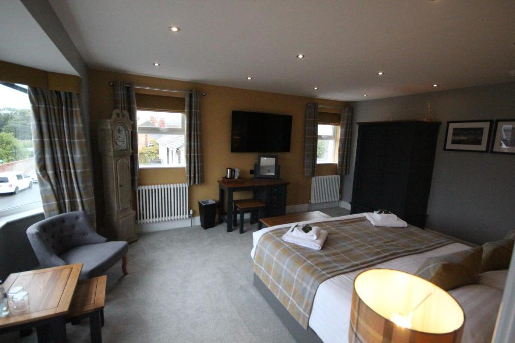 a hotel room with a bed and a couch and a tv at The Sunningdale in Bamburgh