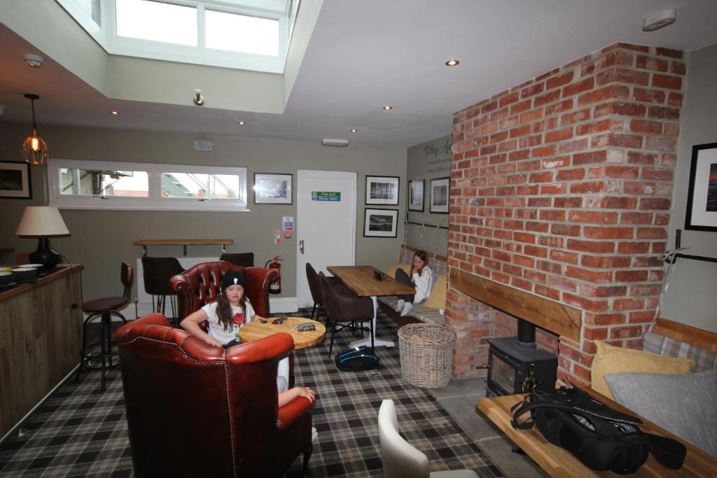 a woman sitting in a chair in a living room with a brick wall at The Sunningdale in Bamburgh