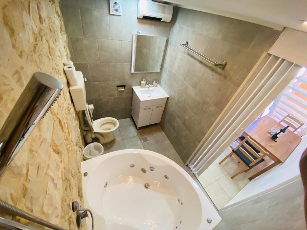 y baño con bañera, aseo y lavamanos. en Zimmer in old City, en Safed