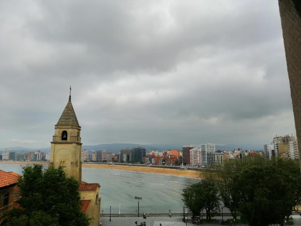 un bâtiment avec une tour d'horloge à côté d'un plan d'eau dans l'établissement Ático en Cimadevilla Mirando al Mar, à Gijón