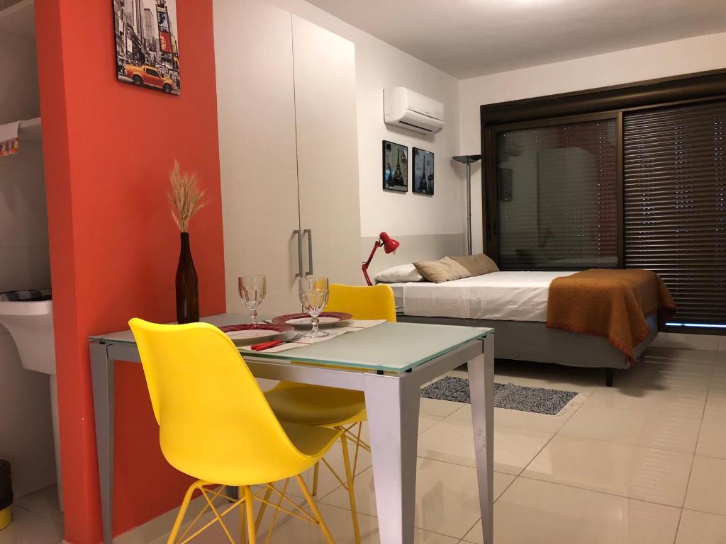 ポルト・アレグレにあるApartamento Perfeito Casemiro, 199 - RETIRADA DAS CHAVES MEDIANTE AGENDAMENTO COM UMA HORA DE ANTECEDÊNCIA COM ANDREIA OU LUISのテーブル、黄色い椅子、ベッドが備わる客室です。