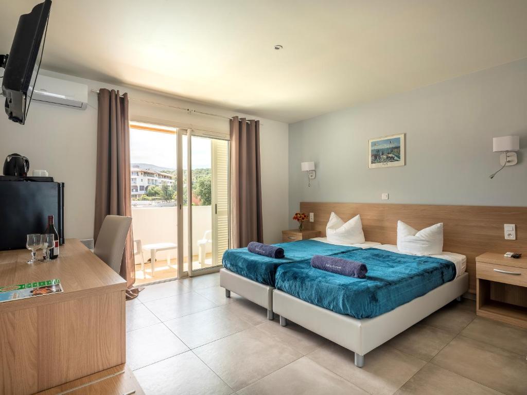 Habitación de hotel con cama y TV en Ferienhotel Maristella, en Algajola