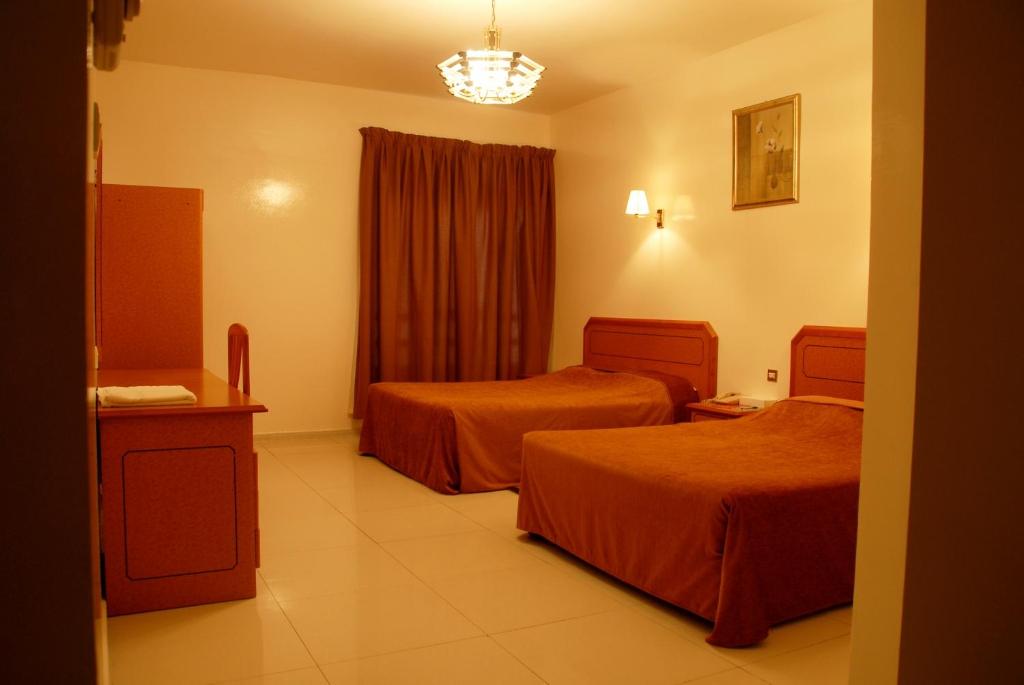 a hotel room with two beds and a window at Basma Residence Hotel Apartments in Sharjah