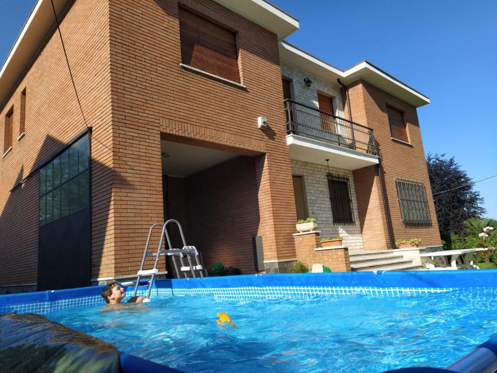 un bambino in una piscina accanto a una casa di Villa Paulette a Bassignana