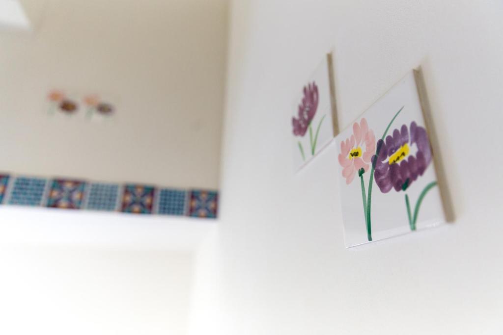 deux images encadrées de fleurs sur un mur dans l'établissement Case Vacanza Le Maioliche, à Marsala