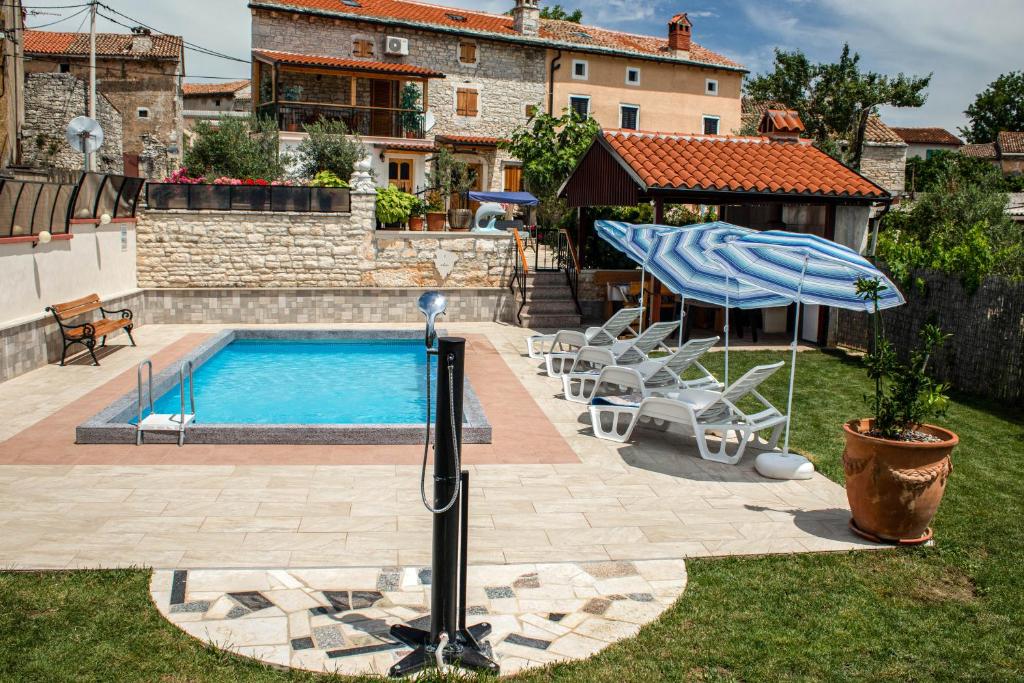 ein Pool mit Sonnenschirm und Stühlen und ein Haus in der Unterkunft Holiday Home Darko in Svetvinčenat