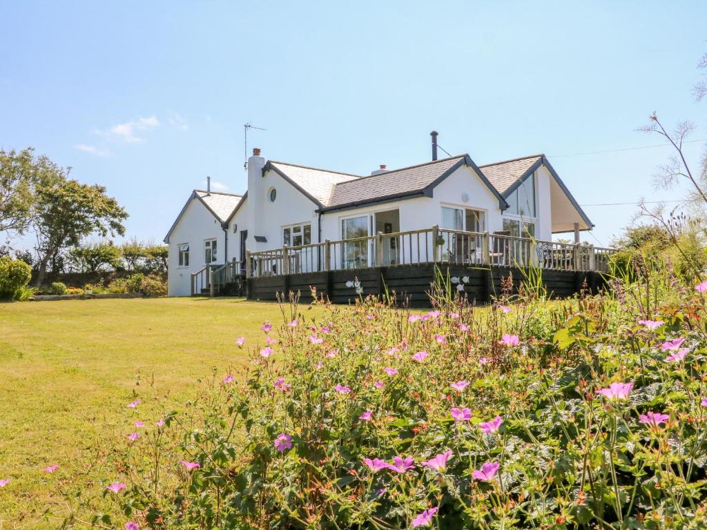 a white house with a deck and flowers at Tidewood in Bideford