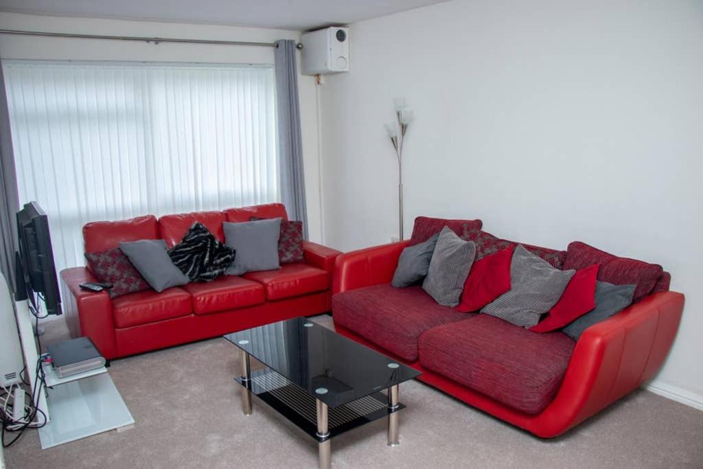 uma sala de estar com dois sofás vermelhos e uma televisão em Crawley Apartment near Gatwick Manor Royal Newly Refurbished Sleeps 4 em Crawley