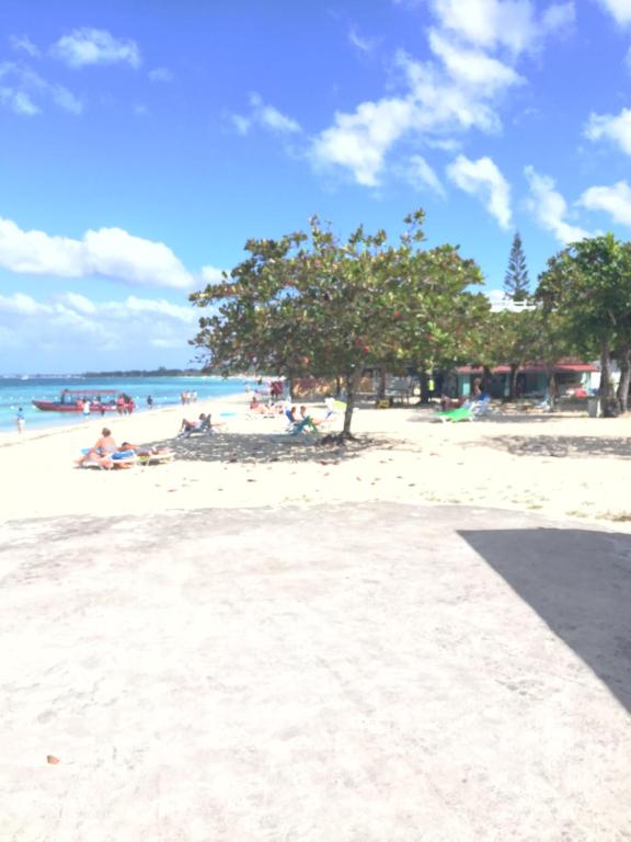Negril Beach Club Condos في نيغريل: مجموعة من الناس يجلسون على الشاطئ