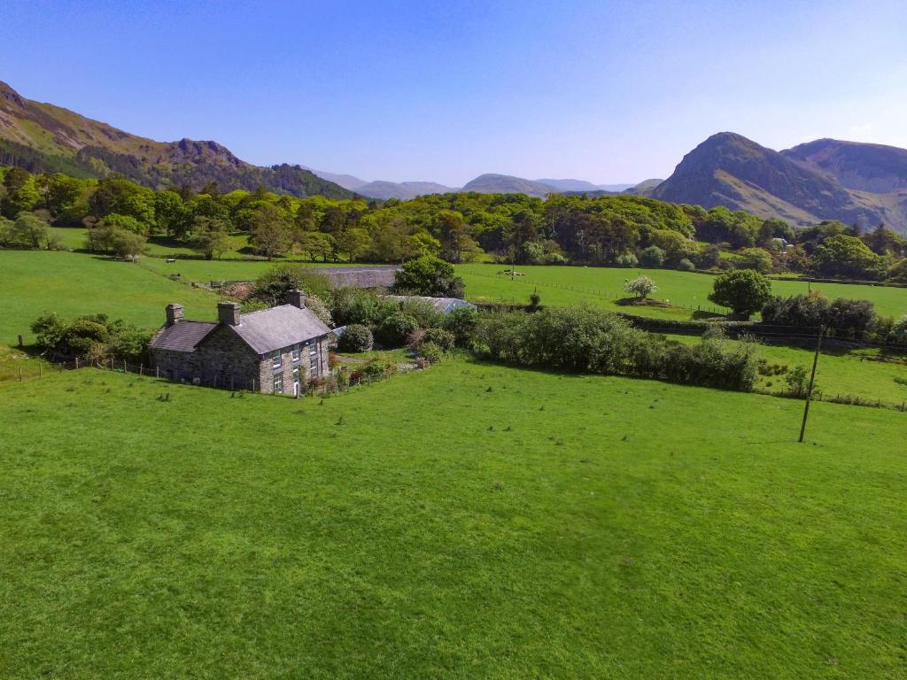 an old house in a field with mountains in the background at Peniarth Ganol in Tywyn