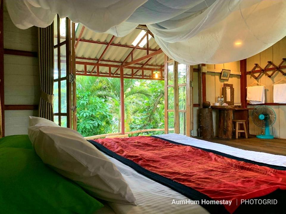 a bedroom with a large bed with a large window at Aum Hum Homestay in Fang