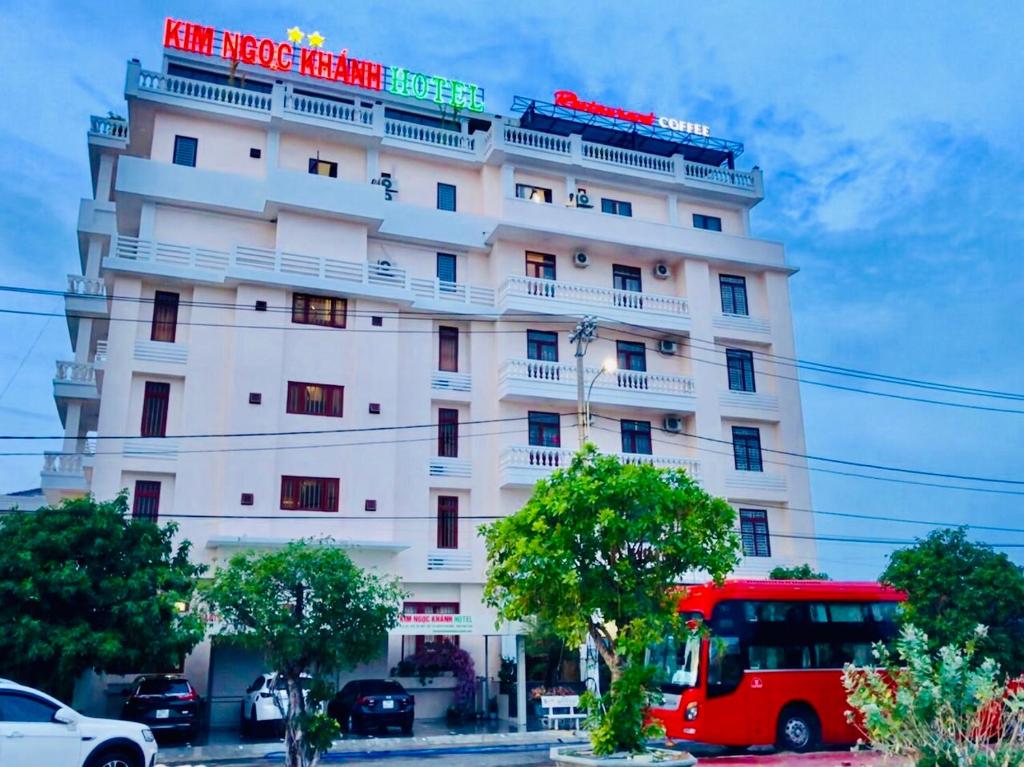 un autobús rojo estacionado frente a un edificio blanco en Kim Ngoc Khanh Hotel en Tuy Hoa