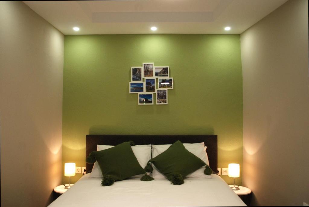 een slaapkamer met een groene muur met een bed en twee lampen bij Sevastie’s home in Samothráki