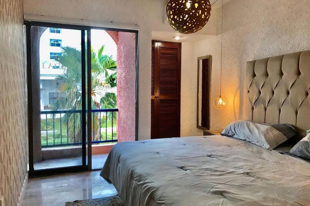 1 dormitorio con cama grande y ventana grande en Tu DEPA en el Paraíso Cancún 2, en Cancún