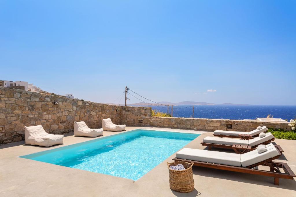 a swimming pool with lounge chairs and a villa at Nikoi Villas in Mikonos