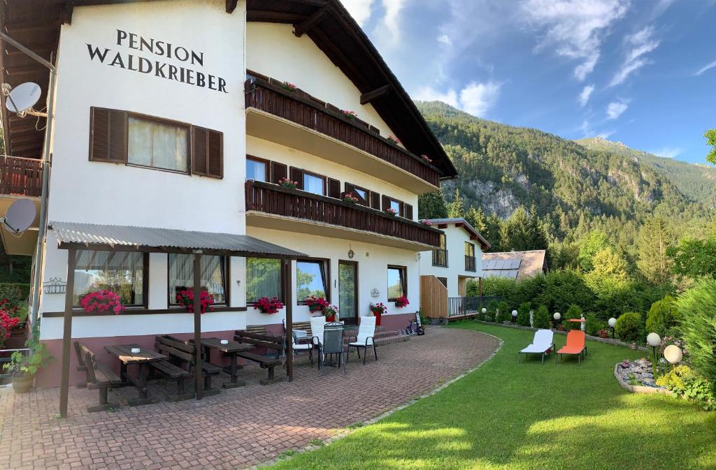 a hotel with tables and chairs outside of it at Pension & Apartments Waldkrieber in Presseggersee