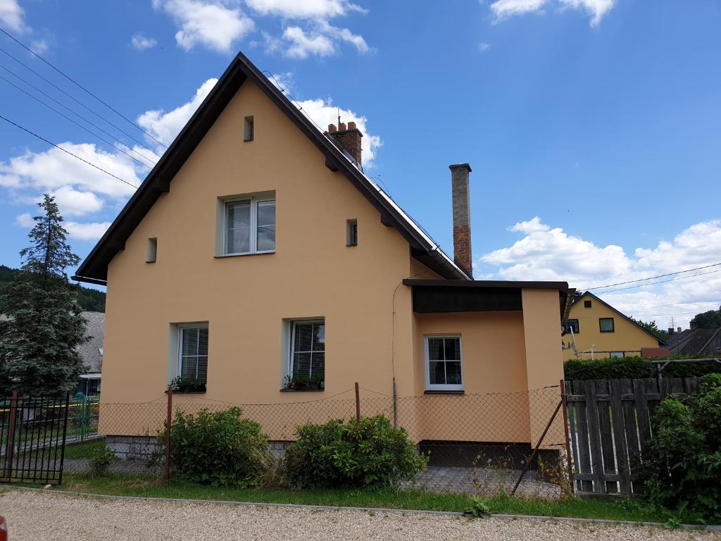ein gelbes Haus mit schwarzem Dach in der Unterkunft Holiday Home Domeček in Lipová-lázně
