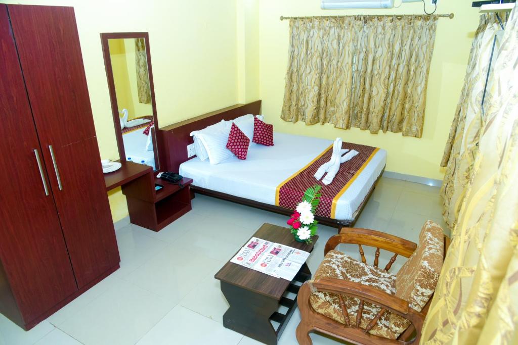 a small room with a bed and a chair at Grand Plaza in Dhārwād