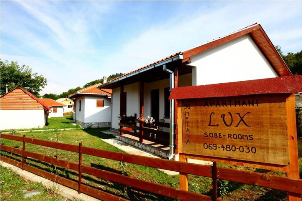 une maison avec un panneau devant une clôture dans l'établissement Apartmani LUX, à Kolašin