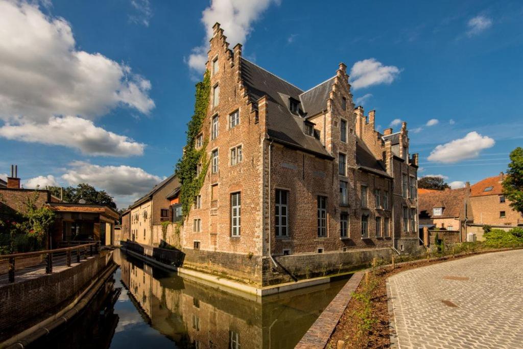 an old brick building next to a canal in a city at Oranje City Hotel in Diest