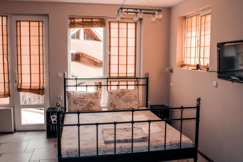 um quarto com uma cama, uma televisão e janelas em La Mer Apartment em Rogachevo