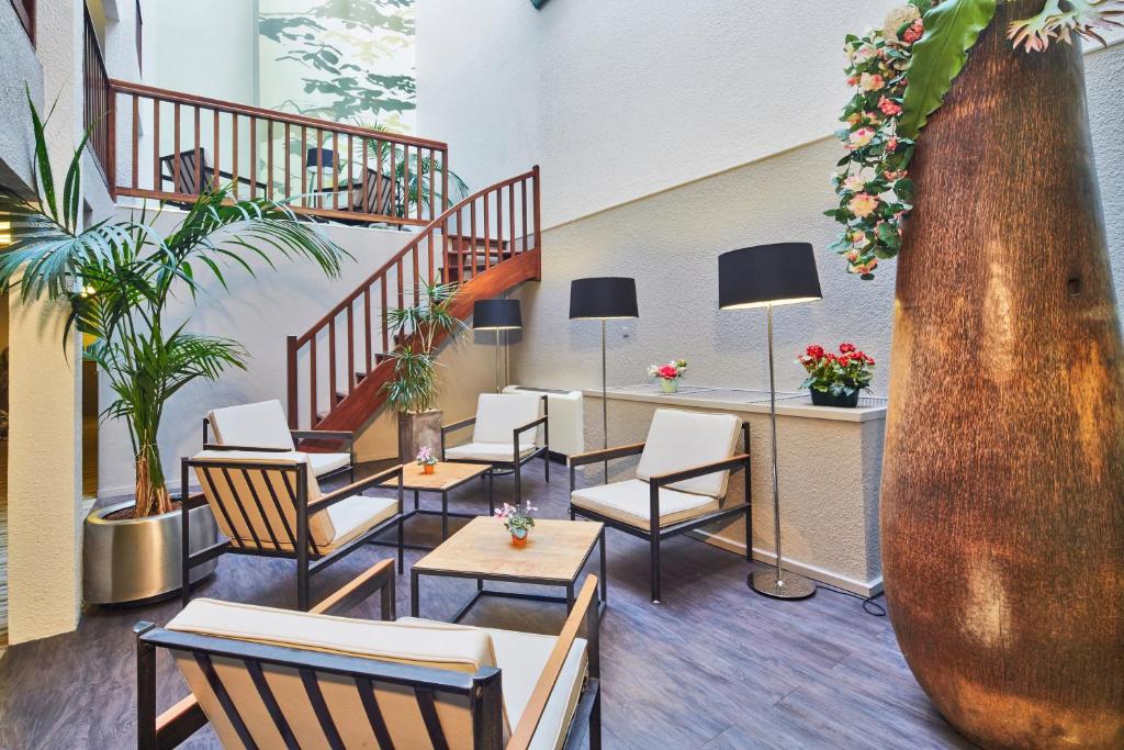 un vestíbulo con sillas y mesas y una escalera en Kyriad Hotel Nevers Centre, en Nevers