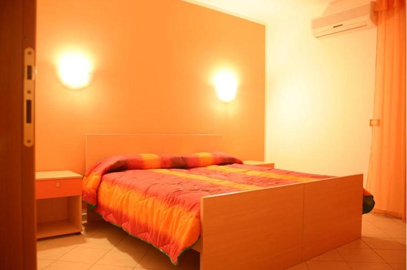 a bedroom with a bed with an orange comforter at L'Arcobaleno in Santa Maria la Palma