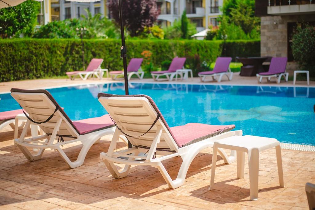 um grupo de cadeiras e um guarda-sol junto a uma piscina em Magnolia Garden em Sunny Beach